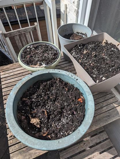 Several pots of soil on a table in a balcony
