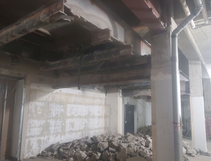 Wider shot were we can see a pile of rubble on the floor below where the cables are damaged.