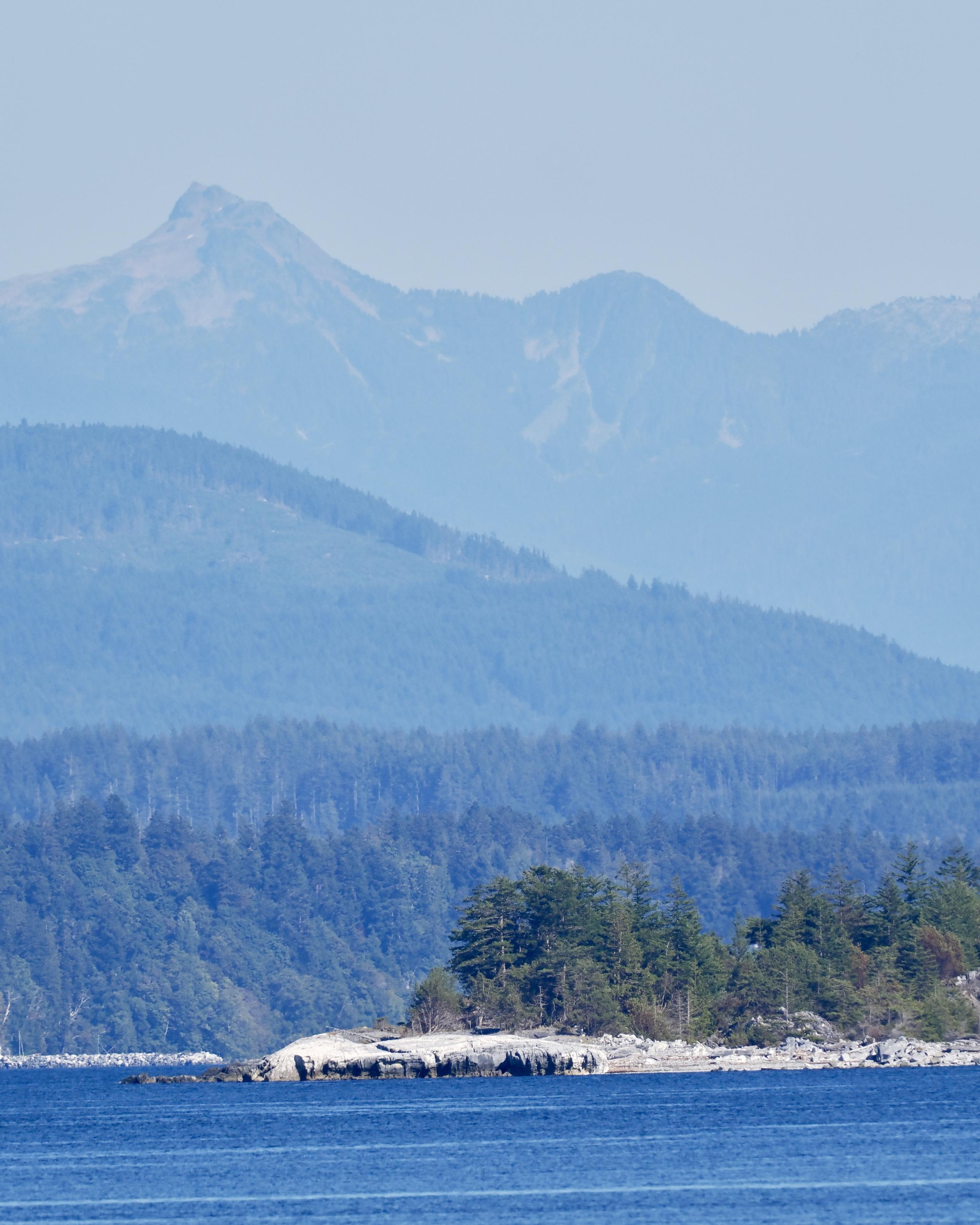 A view from the ferry approaching the Sunshine Coast, rounding Texas’s Island.

Blue water, a rocky shore on a treed island, backdropped by at least three levels of (increasingly bluer, hazier, taller) hills into mountains.