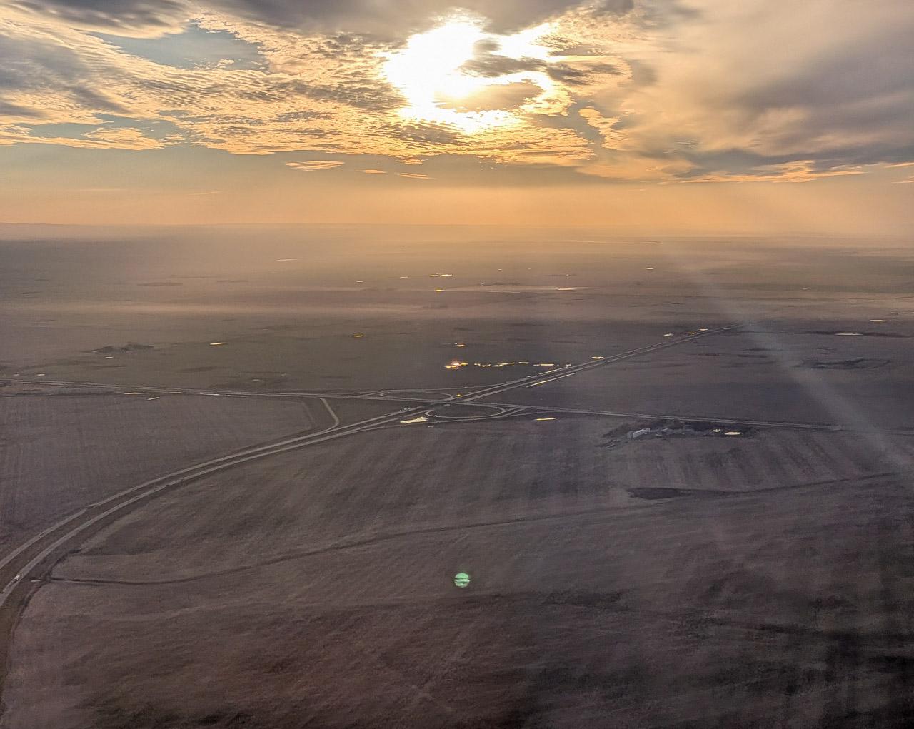 Aerial photo over the prairies near a city featuring highway infrastructure on the ground.