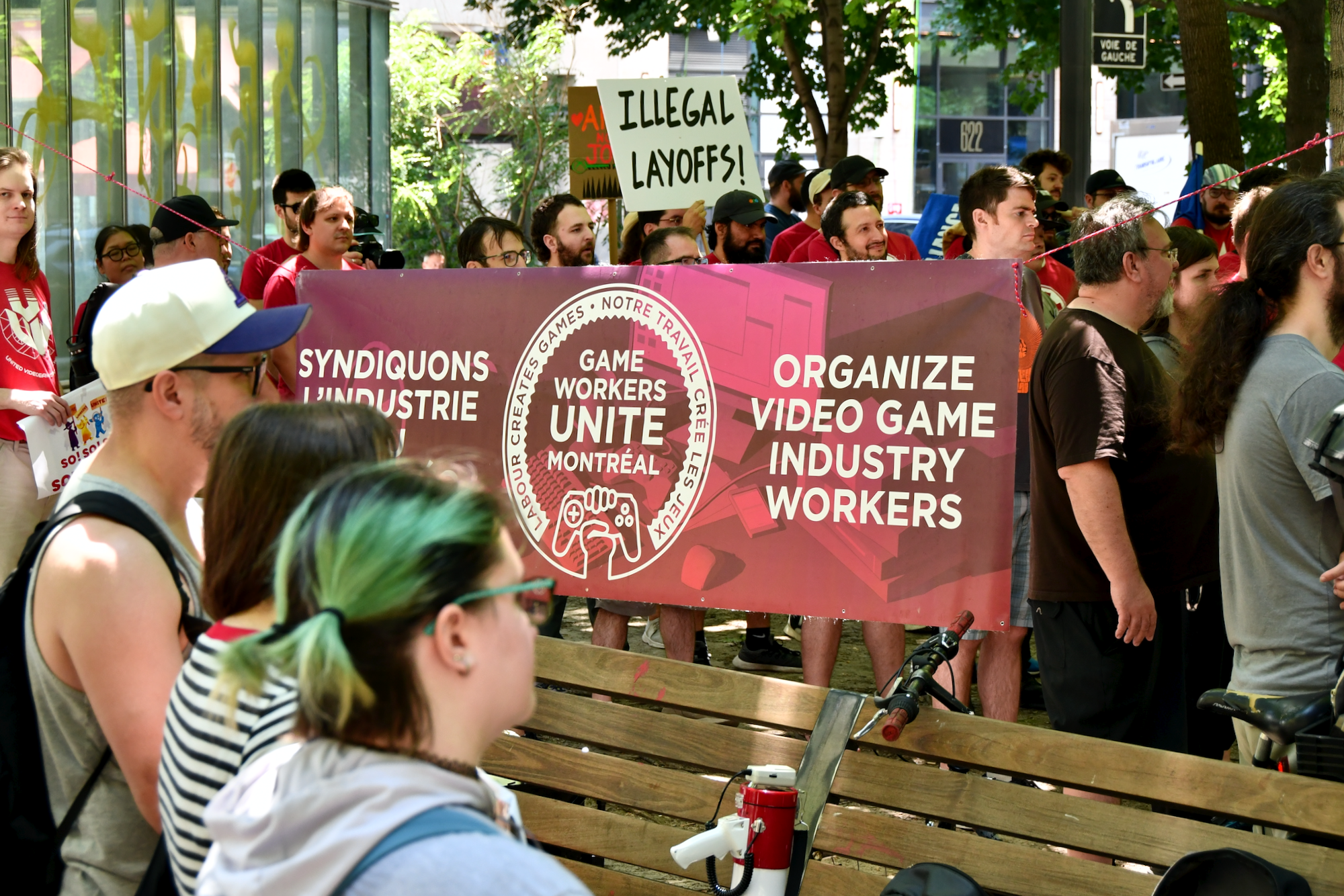Dans la foule, la bannière de Game Workers Unite Montréal avec sa mission: syndiquons l'industrie du jeu vidéo.